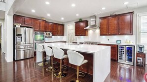 Une cuisine moderne avec des meubles en bois, des appareils en acier inoxydable et un îlot central doté de tabourets de bar.