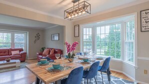 Un coin repas avec une table en bois dressée pour quatre personnes, des chaises bleues et un luminaire suspendu moderne.