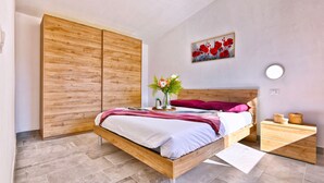 Una camera da letto moderna con un letto di legno, un comodino, un tavolino da notte e un'opera d'arte appesa al muro.