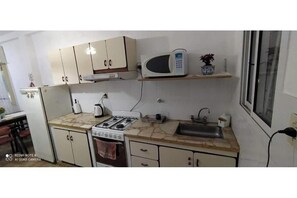 Een magnetron, een oven, een waterkoker, kookgerei, borden en bestek