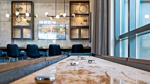 A long, polished table with a few objects on it, surrounded by dark chairs, in a modern room with a large window and decorative lighting. - Sable 504 - One Bedroom (Minneapolis)