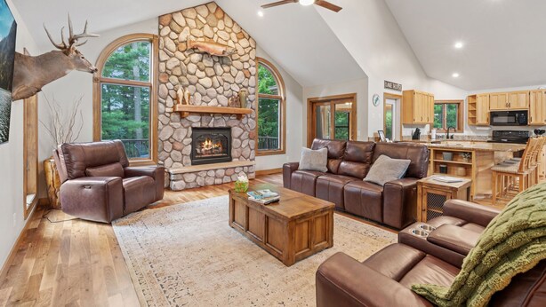 A spacious living room with a stone fireplace, leather furniture, and a view of the outdoors. - Eagle Ridge (Menomonie)