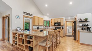 A spacious kitchen with wooden cabinets, a granite countertop, and a central island with bar stools. - Eagle Ridge (Menomonie)