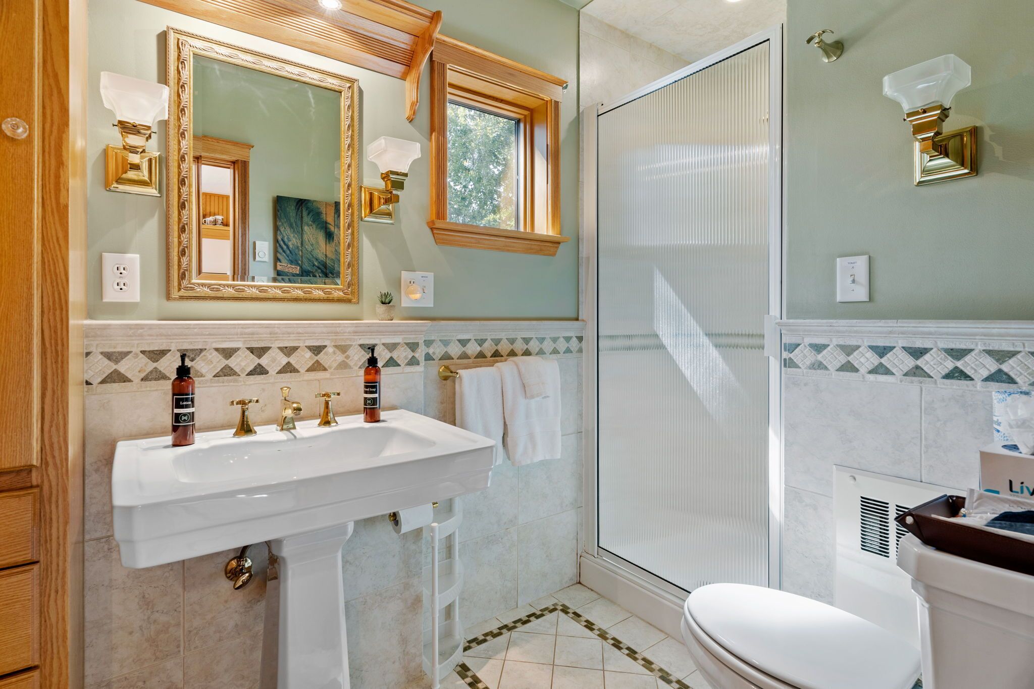 Un baño con un espejo grande, dos lavamanos, una ducha y un inodoro.