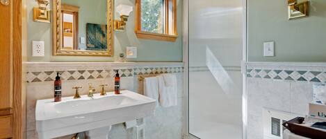 Un baño con un espejo grande, dos lavamanos, una ducha y un inodoro.