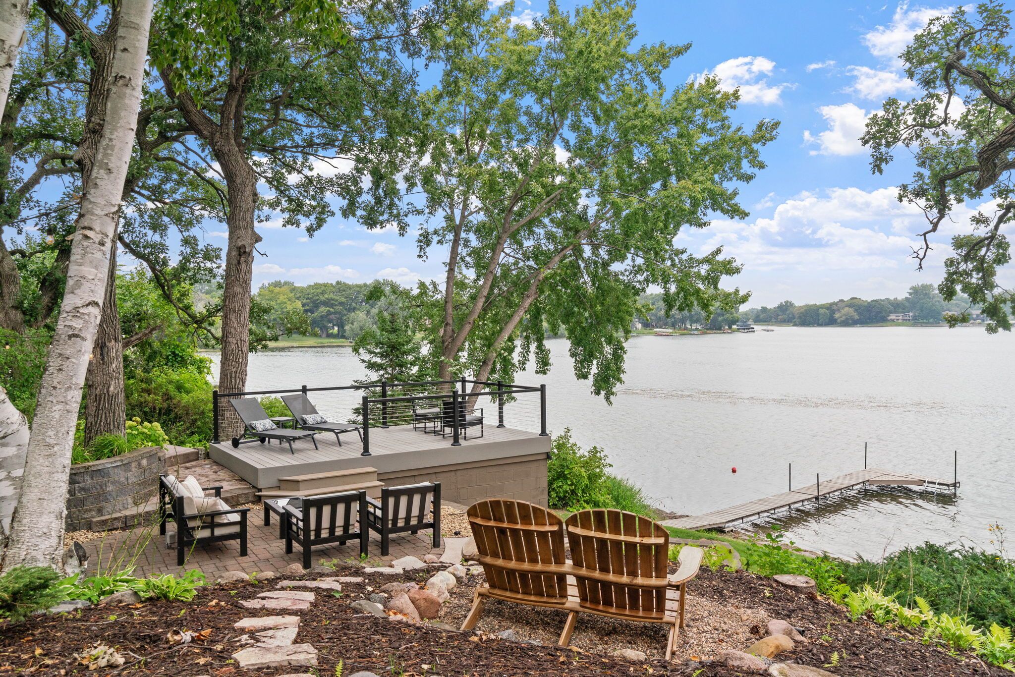 Terraza junto al lago con mobiliario exterior y vista al lago.