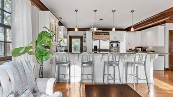 Uma cozinha moderna com armários brancos, eletrodomésticos de aço inoxidável e uma ilha central com banquetas.