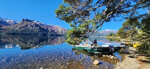 Ein Boot namens "KARU" liegt an einem klaren See vor einer Bergkulisse.