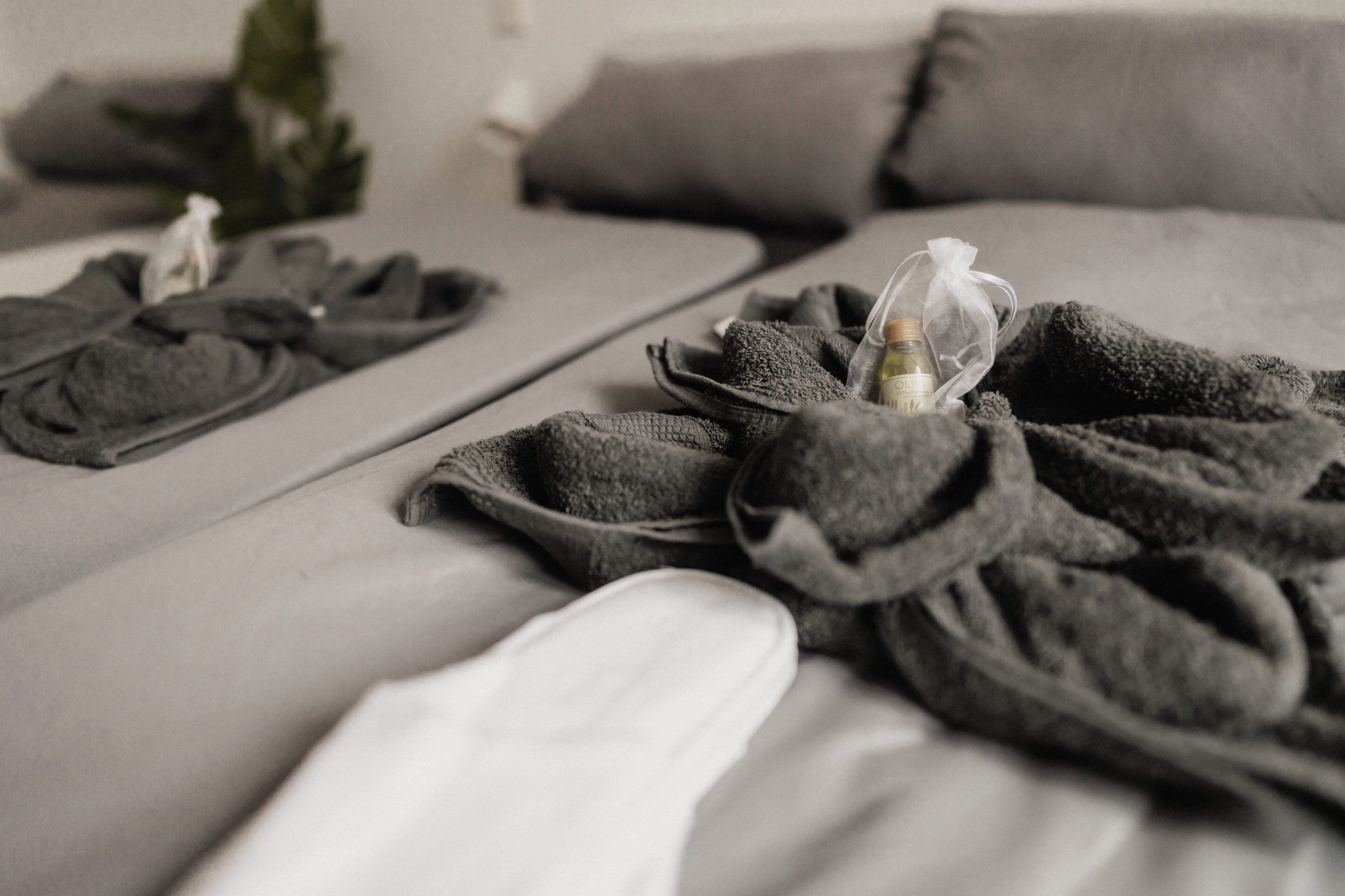 Una cama con una manta gris y una botella de loción.