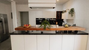 A modern kitchen with a wooden countertop, white cabinets, and a central island with a plant. - Goldstadtloft (Pforzheim)