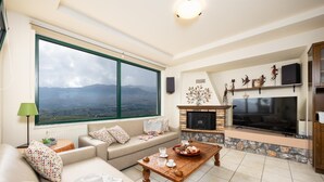 A living room with a large window, a fireplace, a TV, and a sofa.