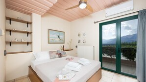 A bedroom with a bed, a ceiling fan, a window with a view of mountains, and a radiator.