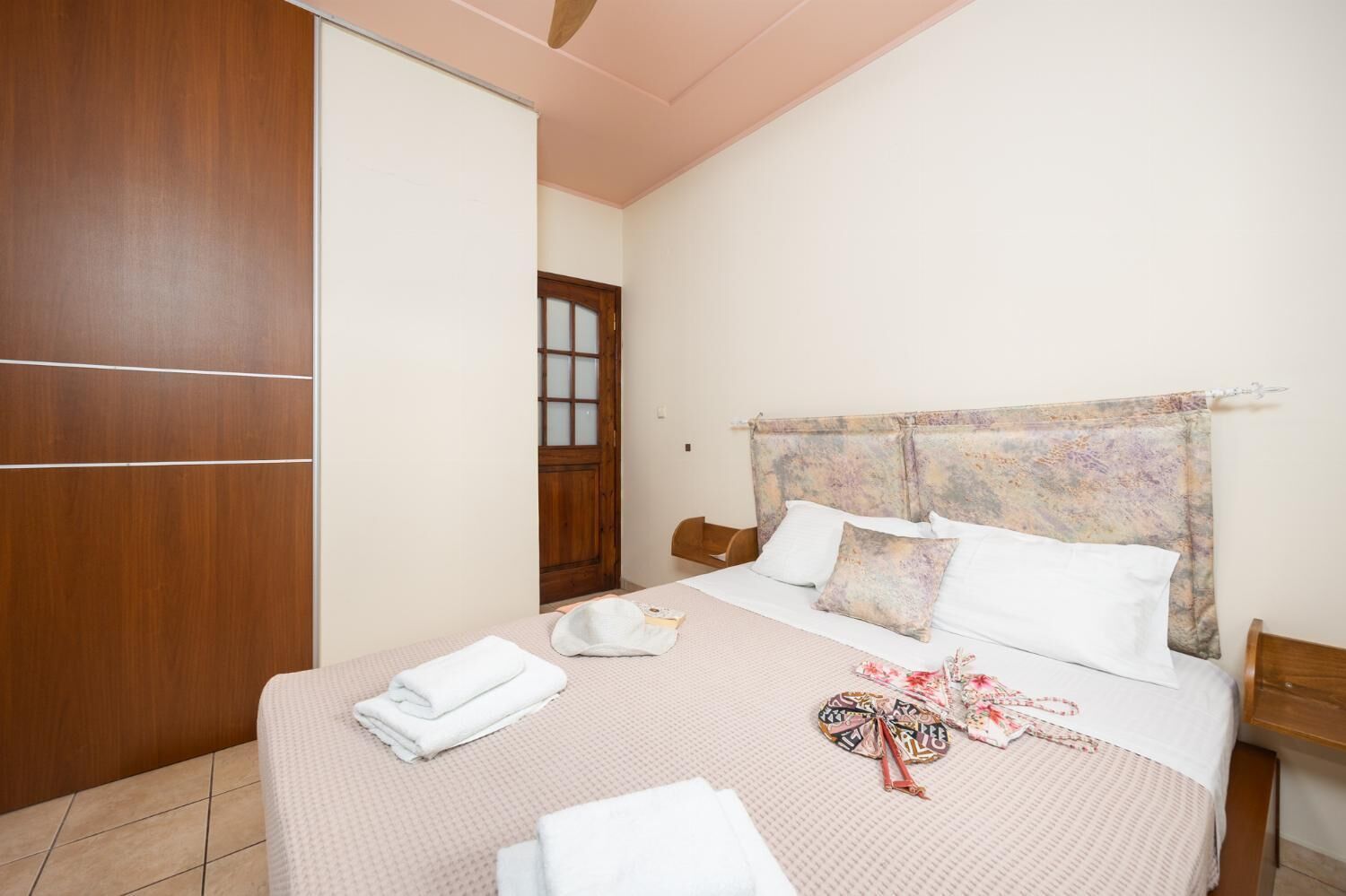 Un dormitorio con cama, almohadas, un armario de madera y una puerta.