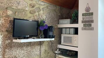 A stone wall with a mounted television, a microwave, and a refrigerator.