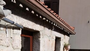 Un edificio de piedra con techo de tejas, una puerta y una pequeña ventana.
