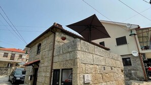 Un edificio de piedra con puerta negra, una ventana pequeña y un cartel que indica un espacio público.