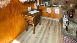 Un interior de madera con pared de piedra, una zona de cocina con estufa y una mesa de comedor.