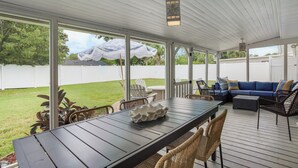 Un patio techado con una mesa de comedor, sillas y un sofá.