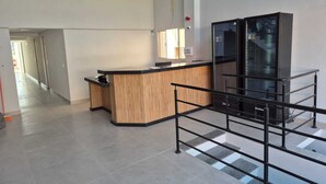A reception area with a wooden reception desk, a glass display cabinet, and a tiled floor. - Hotel Fortunato (Braganca Paulista)