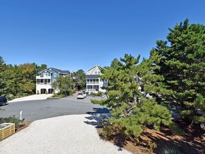 A residential area with two houses, a driveway, and surrounding trees.