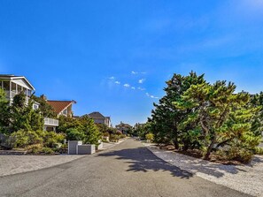 Een woonstraat met huizen aan beide zijden, een heldere lucht en bomen langs de weg.
