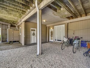 Un espace extérieur abrité, doté d’un sol en gravier, d’un vélo et d’une porte donnant accès à un bâtiment.