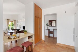 Une cuisine moderne avec un coin repas, des meubles en bois et une vue sur l’extérieur.