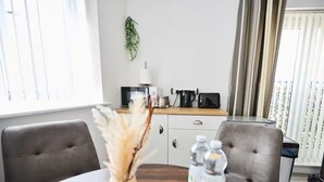 A dining area with a wooden table, two chairs, a vase with dried plants, and two water bottles. - Ampee Guest Suite-Free Parking (Liverpool)