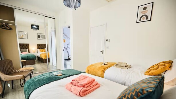 A hotel room with two beds, a chair, a bathroom, and a door. - Ampee Guest Suite-Free Parking (Liverpool)