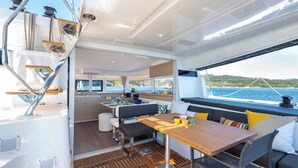 Een modern jachtinterieur met een eetgedeelte, keuken en zitplaatsen bij het raam.