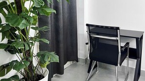 A corner of a room with a white potted plant, a black desk, and a grey curtain. - Hai anh home Hai Phong (Ho Chi Minh City)