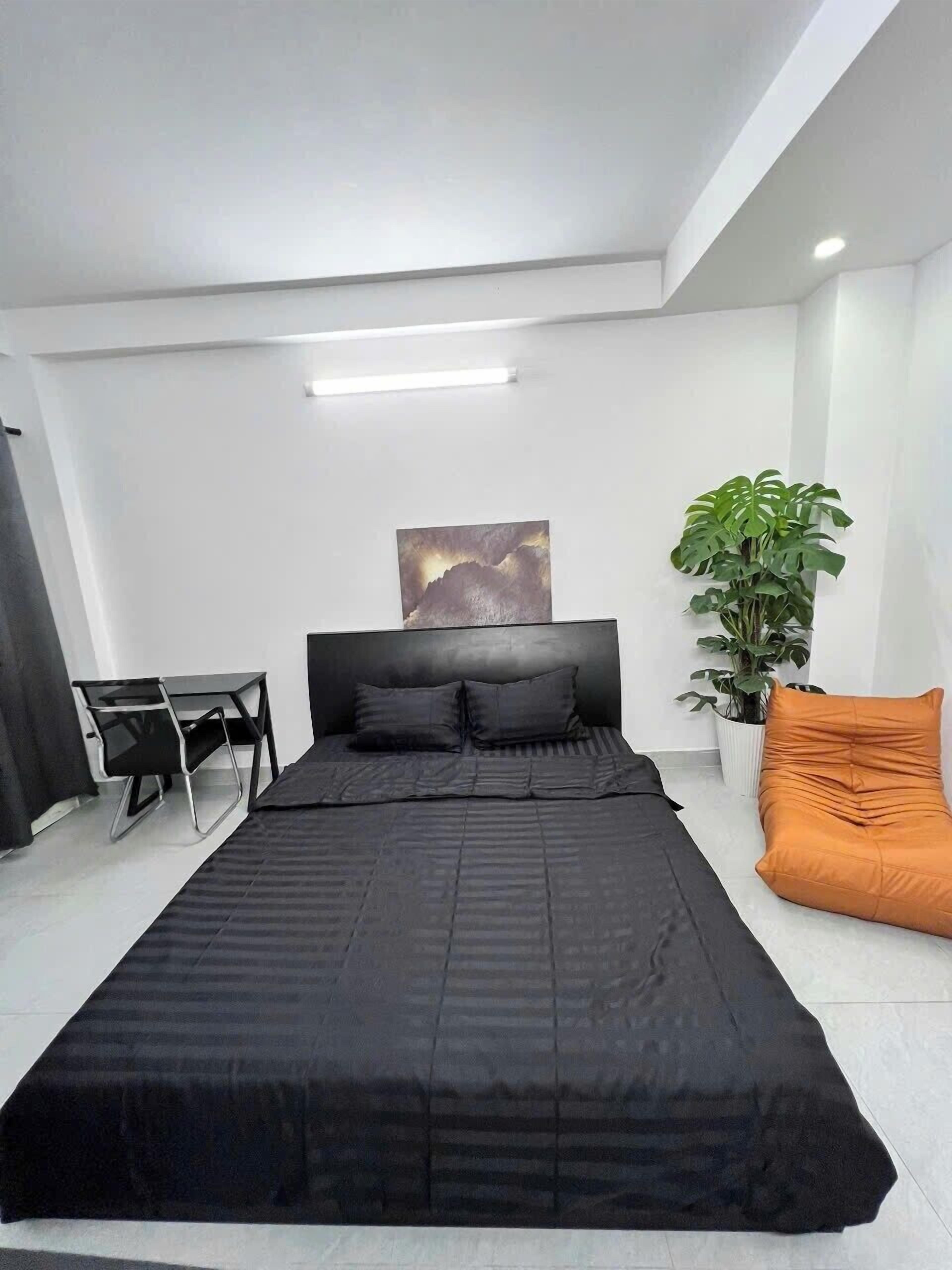 Een moderne slaapkamer met een groot bed, een bureau en een potplant.