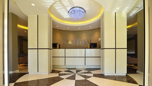 A hotel reception area with a modern design, featuring a chandelier, a reception desk, and a check-in counter.