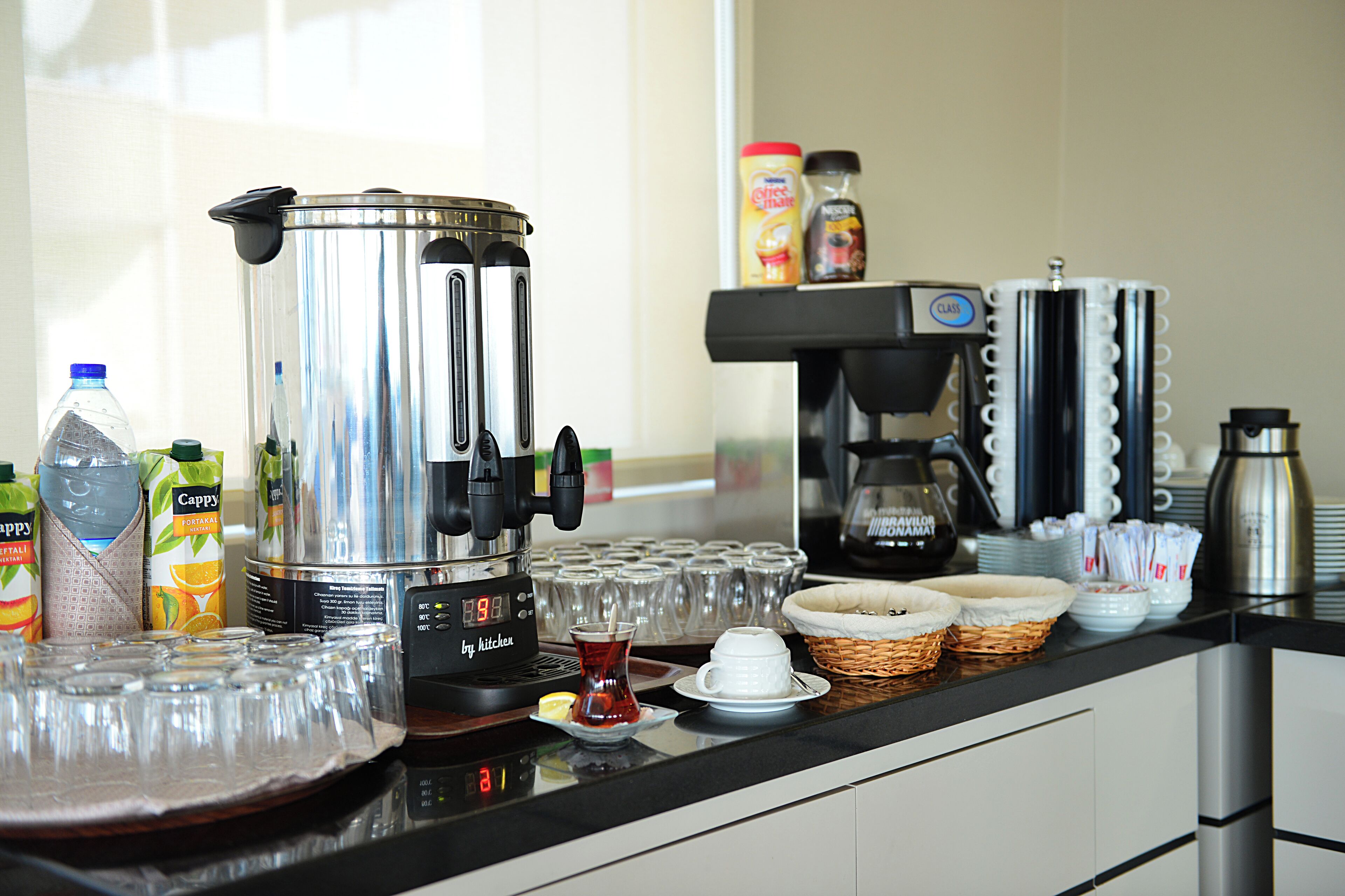 Kaffestation med kaffemaskine, kopper og tilbehør.