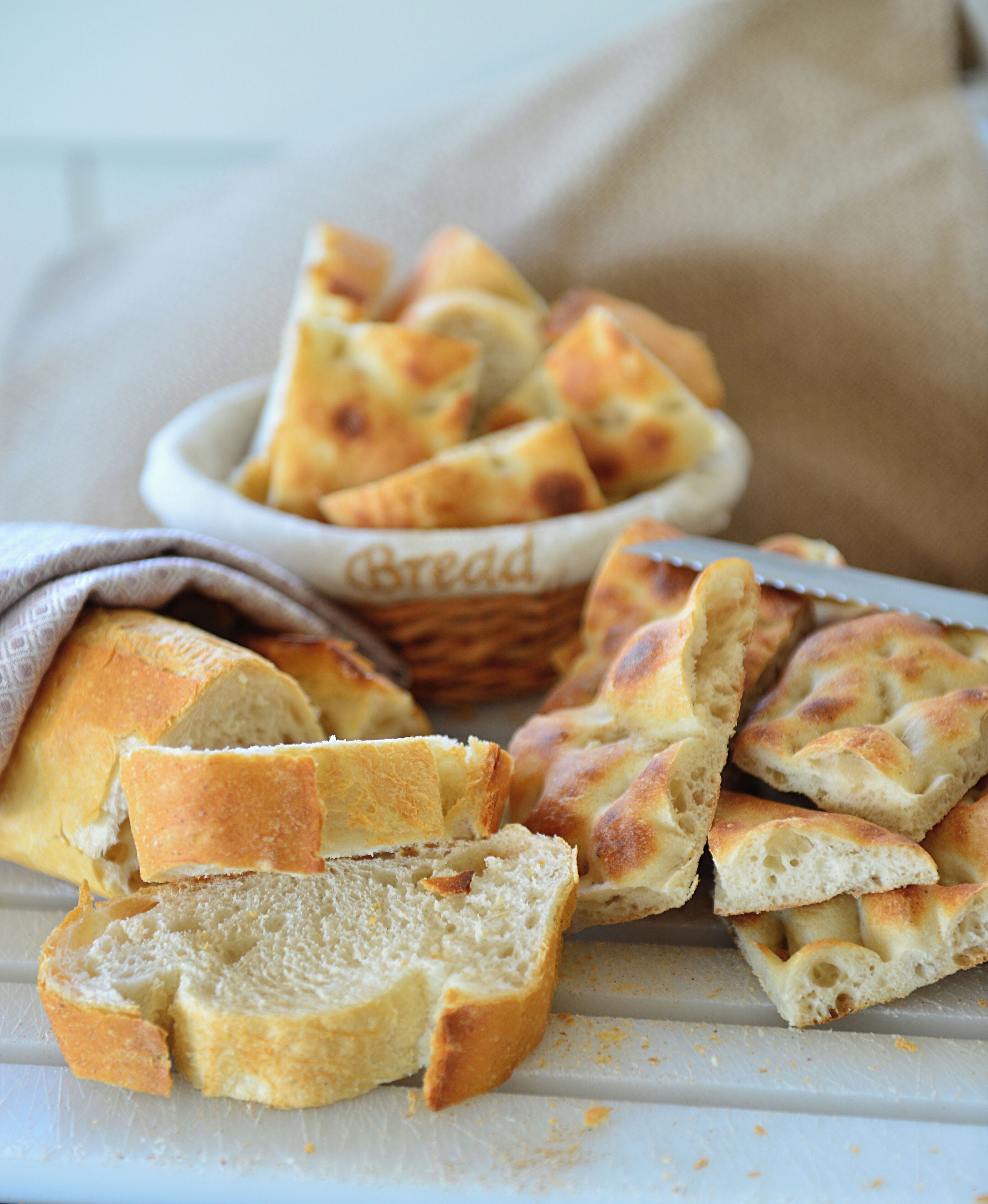 Uma cesta com pão fatiado sobre uma superfície branca.