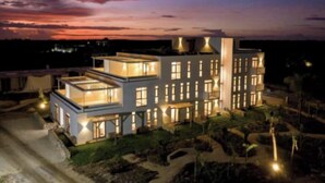 Et moderne hotel med flere etager, oplyste vinduer og en anlagt have.