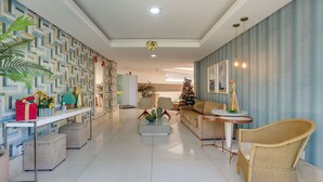 Un salon moderne avec un mur orné d’un motif géométrique, un sapin de Noël et un fauteuil en osier.