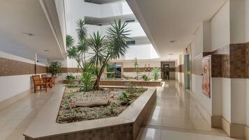Amplo espaço interno com jardim central, assentos e teto alto com claraboias.