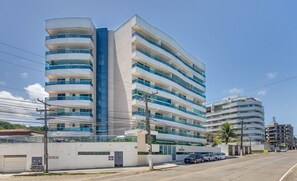Un hotel de varios pisos con balcones, un estacionamiento y cielo despejado.