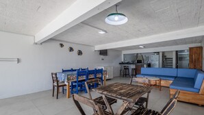 Un'ampia zona giorno con tavolo da pranzo, sedie blu, un divano blu e una cucina sullo sfondo.