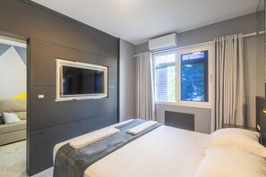 A modern hotel room with a large bed, a flat-screen TV mounted on the wall, a window with curtains, and an air conditioning unit. - Confort y Estilo en Itacorubi, Floripa Apc0207 (Florianópolis)