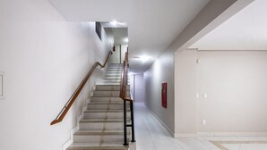 A staircase with a wooden handrail, white walls, and a tiled floor. - Confort y Estilo en Itacorubi, Floripa Apc0207 (Florianópolis)