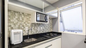 A modern kitchen with a black countertop, a built-in microwave, a gas stove, and a window with a view. - Confort y Estilo en Itacorubi, Floripa Apc0207 (Florianópolis)