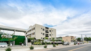 A street view with a pharmacy, a multi-story building, and a green storefront. - Apart Near the Beach in Cond. w/ Pool Adc0205 (Florianópolis)