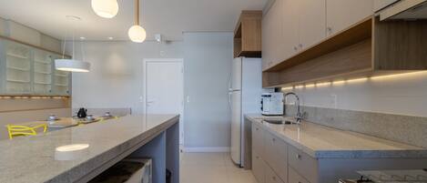 Una cocina moderna con encimera de granito, electrodomésticos de acero inoxidable e iluminación colgante.