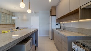 A modern kitchen with a granite countertop, stainless steel appliances, and pendant lighting. - Apart Near the Beach in Cond. w/ Pool Adc0205 (Florianópolis)