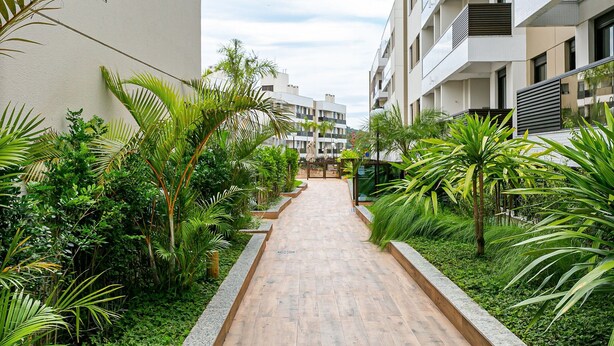 A pathway flanked by lush greenery and modern buildings. - Apartments With Pools 200m From the sea Floripa-sc ADC (Florianópolis)