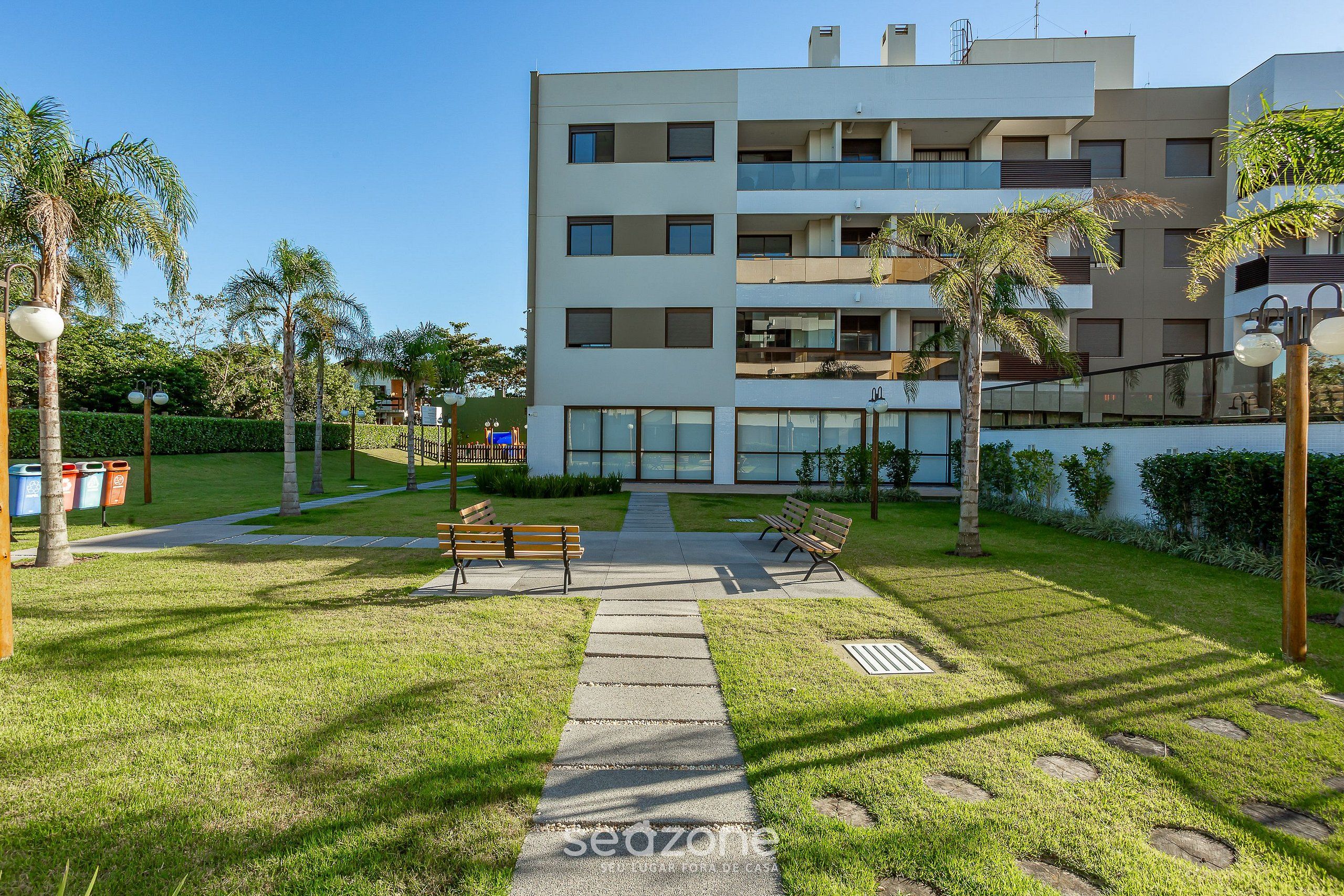 Un immeuble d’appartements moderne doté d’une cour intérieure, de bancs et de palmiers.