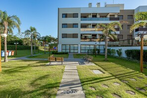 Un moderno edificio de apartamentos con un patio central, bancos y palmeras.