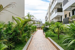 Un sendero bordeado por abundante vegetación y edificios modernos.